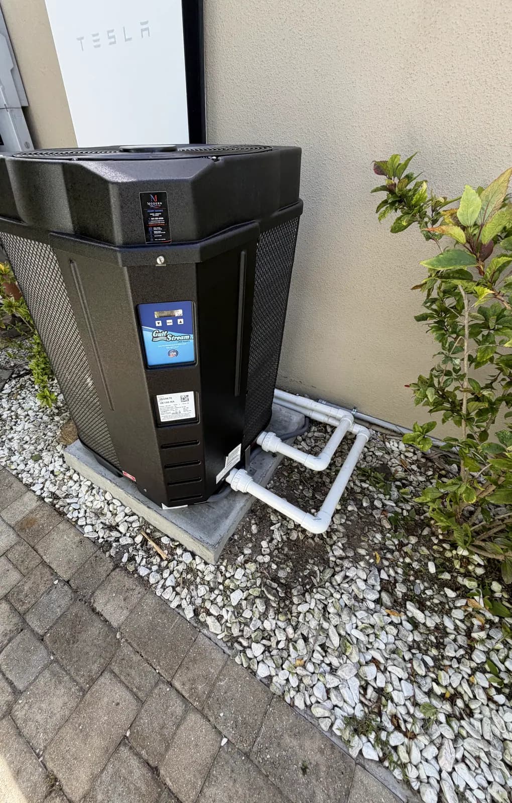 GulfStream HE150-RA pool heat pump on a concrete pad in a white rock bed beside a paver walkway